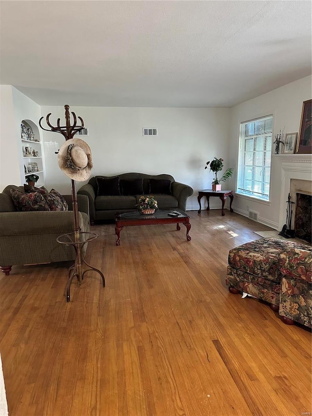 living room with built in features and wood-type flooring