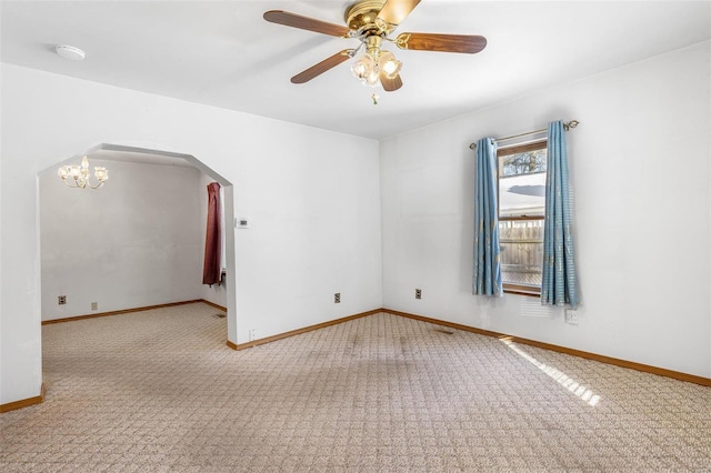 carpeted empty room featuring ceiling fan with notable chandelier