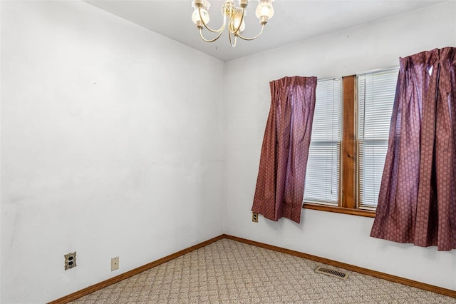 carpeted empty room featuring a notable chandelier