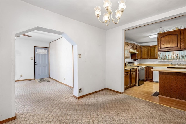 kitchen with white dishwasher, pendant lighting, gas range oven, and light colored carpet