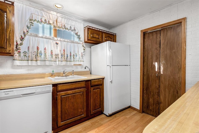 kitchen with white appliances, light wood-type flooring, and sink