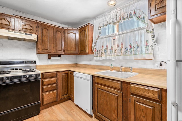 kitchen featuring sink, white appliances, and light wood-type flooring