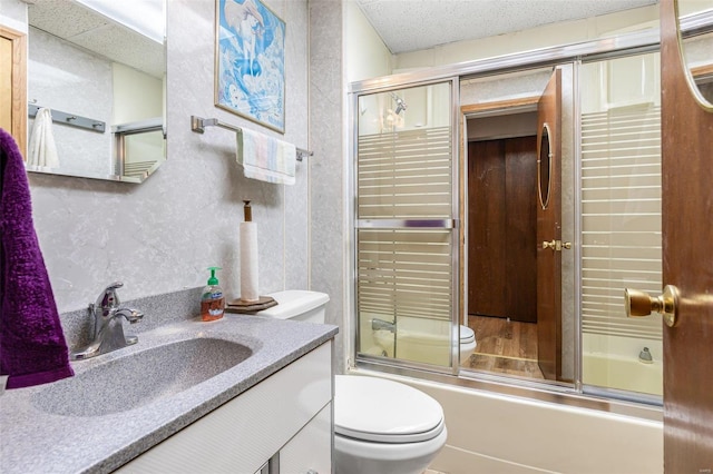 full bathroom with a textured ceiling, shower / bath combination with glass door, vanity, and toilet