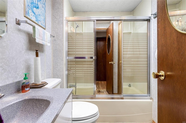 full bathroom featuring toilet, a textured ceiling, enclosed tub / shower combo, and vanity