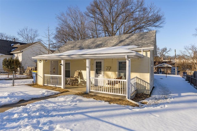 bungalow-style house featuring a porch, fence, and roof with shingles