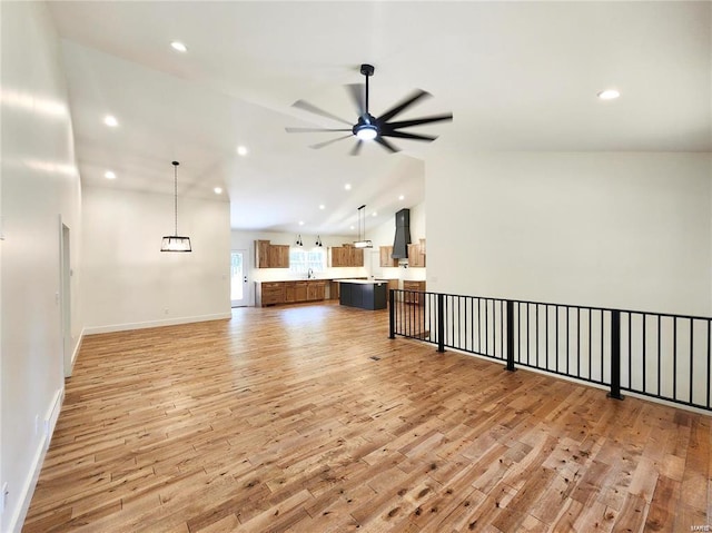 living room with lofted ceiling, light wood-type flooring, ceiling fan, and sink