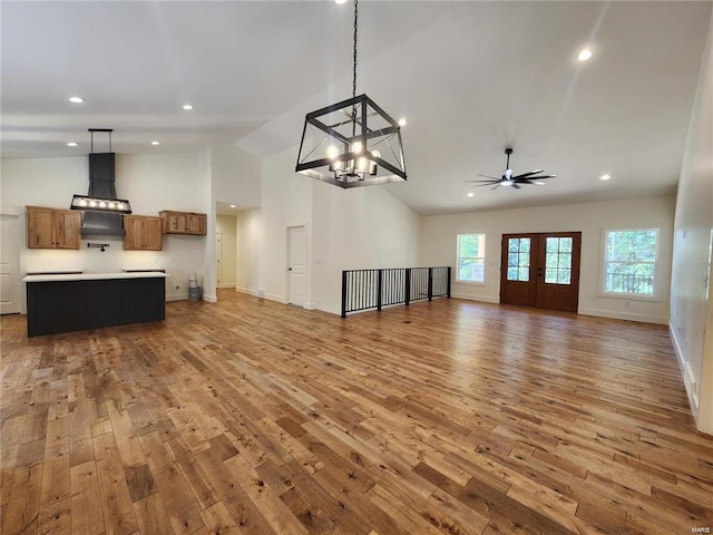 unfurnished living room with french doors, high vaulted ceiling, ceiling fan with notable chandelier, and wood-type flooring