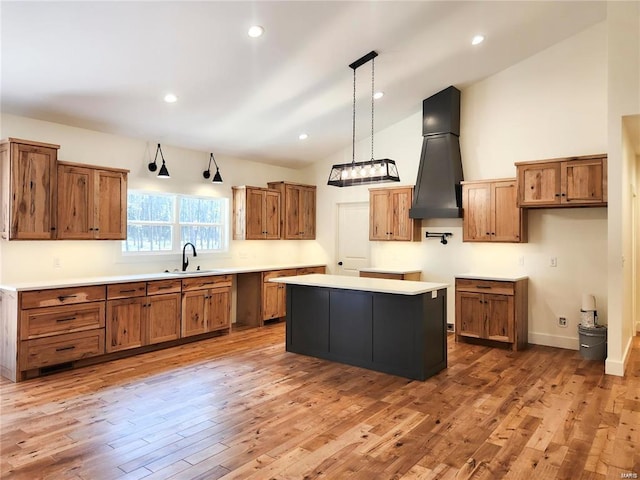 kitchen with hardwood / wood-style floors, vaulted ceiling, a kitchen island, sink, and decorative light fixtures