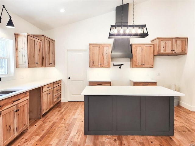 kitchen with decorative light fixtures, wall chimney exhaust hood, vaulted ceiling, and a center island