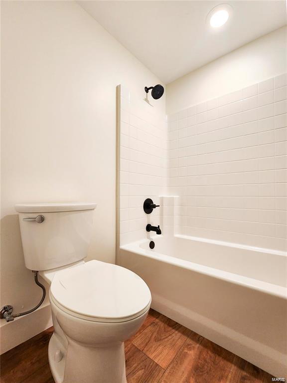 bathroom featuring toilet, hardwood / wood-style floors, and bathtub / shower combination