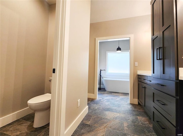 bathroom with toilet, vanity, and a tub to relax in