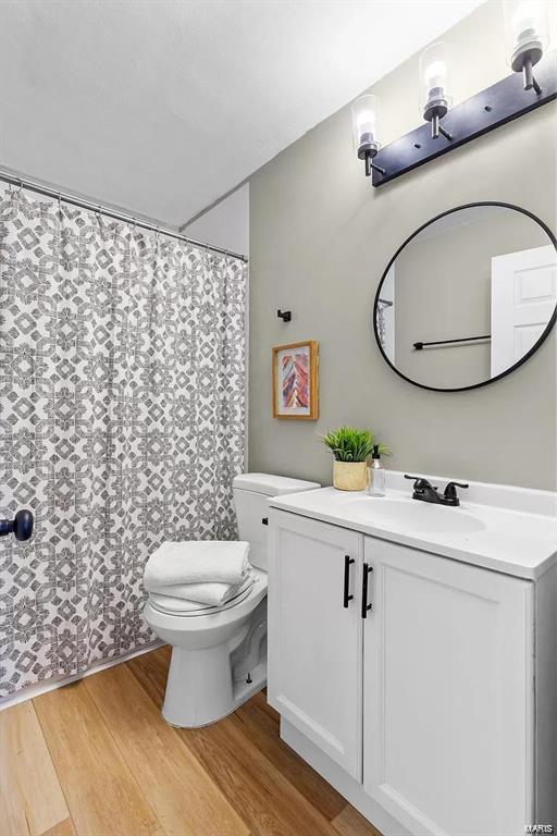 bathroom with toilet, vanity, and hardwood / wood-style floors