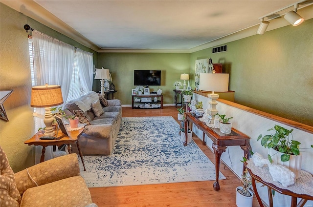 living room with hardwood / wood-style flooring, ornamental molding, and track lighting