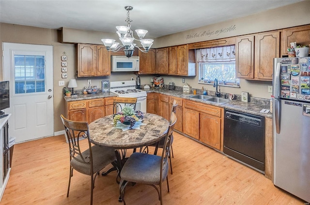 kitchen with white appliances, decorative light fixtures, an inviting chandelier, sink, and light hardwood / wood-style flooring