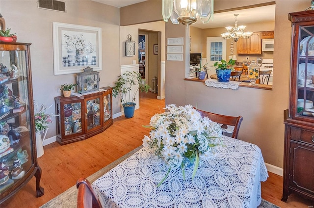 dining space with an inviting chandelier and light hardwood / wood-style floors