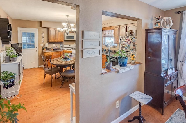 kitchen featuring light wood-type flooring, an inviting chandelier, a healthy amount of sunlight, and hanging light fixtures