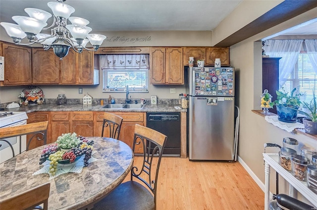 kitchen featuring white appliances, dark stone countertops, sink, a notable chandelier, and light hardwood / wood-style flooring