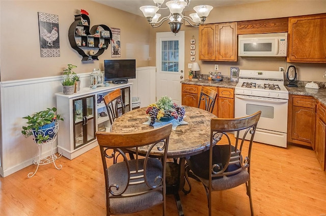 kitchen with light hardwood / wood-style floors, white appliances, hanging light fixtures, and an inviting chandelier