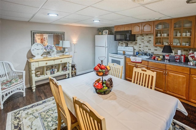 kitchen with a paneled ceiling, backsplash, dark hardwood / wood-style flooring, and white appliances