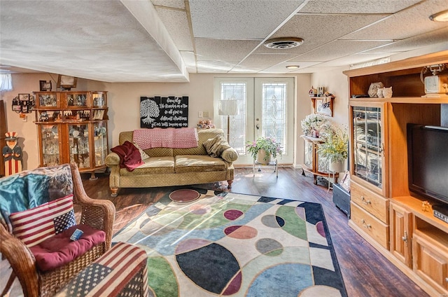 living room with dark hardwood / wood-style floors, a drop ceiling, and french doors