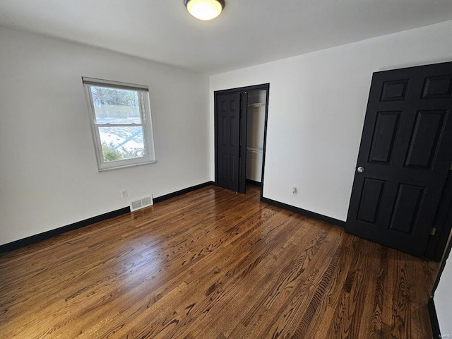 unfurnished bedroom featuring a closet and dark hardwood / wood-style flooring