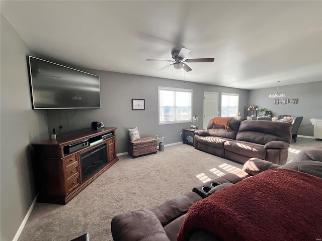 carpeted living room featuring ceiling fan with notable chandelier