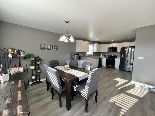 dining space with a notable chandelier, sink, and hardwood / wood-style flooring