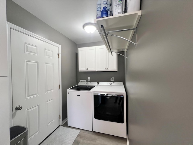 laundry room featuring washer and dryer, light hardwood / wood-style floors, and cabinets