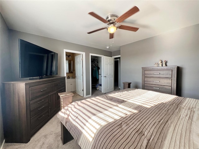 bedroom with ceiling fan, light colored carpet, connected bathroom, a walk in closet, and a closet