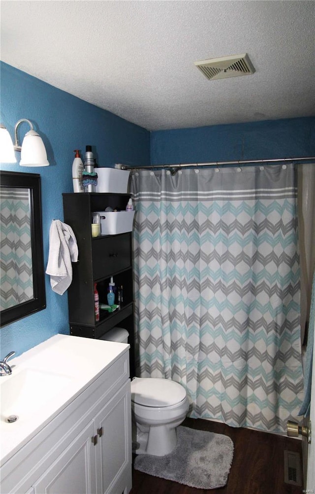 bathroom featuring toilet, a textured ceiling, a shower with shower curtain, and vanity