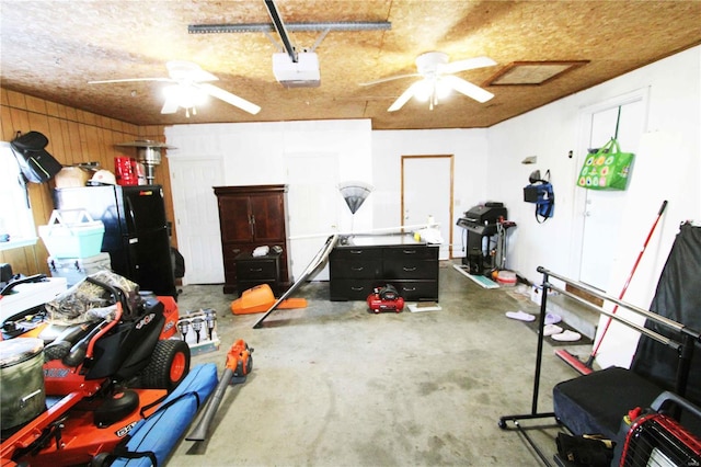 garage featuring a garage door opener, wooden walls, and black refrigerator