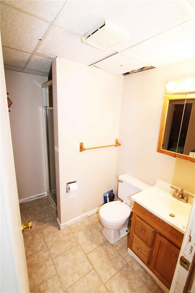 bathroom featuring tile patterned flooring, a paneled ceiling, toilet, walk in shower, and vanity