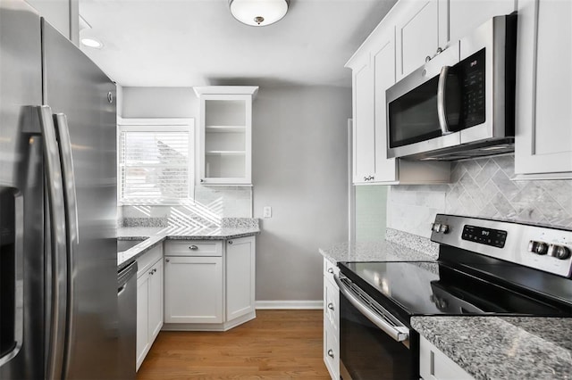 kitchen featuring white cabinets, appliances with stainless steel finishes, light stone counters, and light hardwood / wood-style flooring