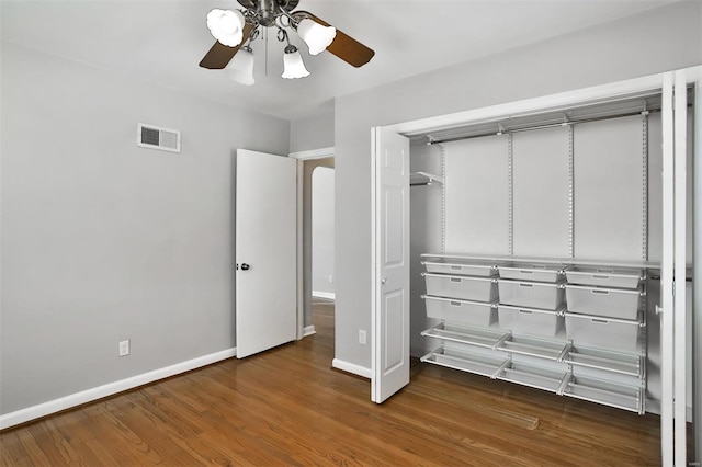 unfurnished bedroom with ceiling fan, dark hardwood / wood-style flooring, and a closet