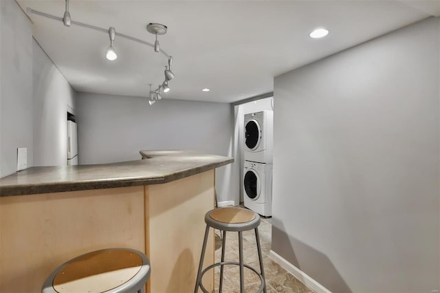 interior space featuring a kitchen breakfast bar, track lighting, and stacked washer and dryer