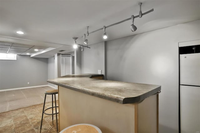 kitchen featuring a kitchen bar, white refrigerator, and track lighting