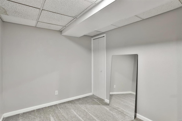 basement with light colored carpet and a drop ceiling