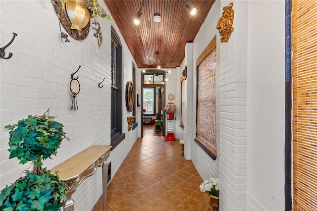 hall featuring wooden ceiling, brick wall, and tile patterned floors