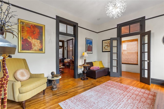 sitting room with french doors, a notable chandelier, and wood-type flooring