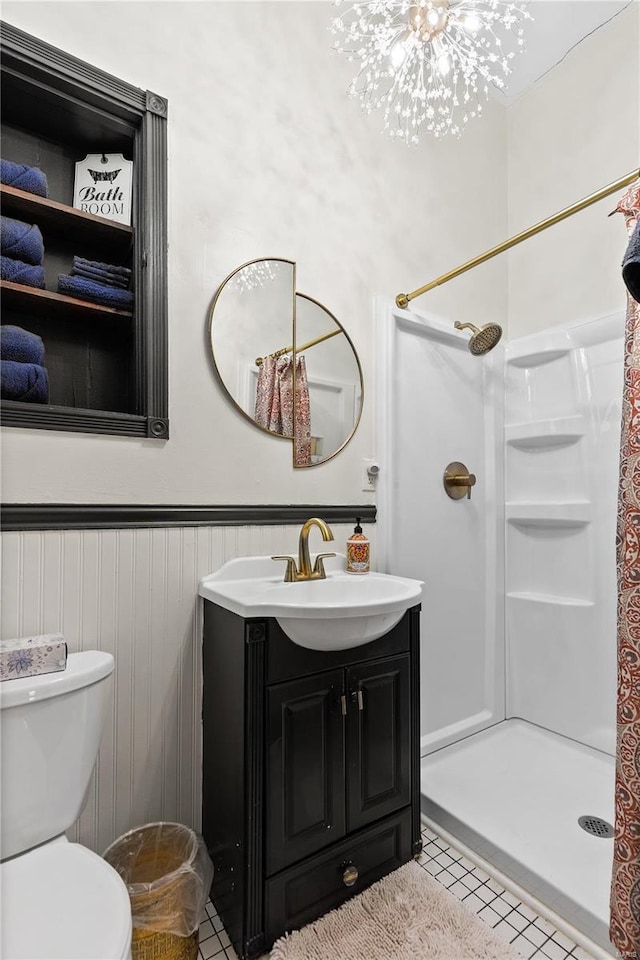 bathroom featuring toilet, vanity, a notable chandelier, tile patterned floors, and a shower