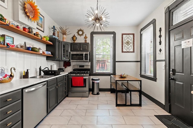 kitchen featuring decorative light fixtures, stainless steel appliances, sink, backsplash, and a chandelier