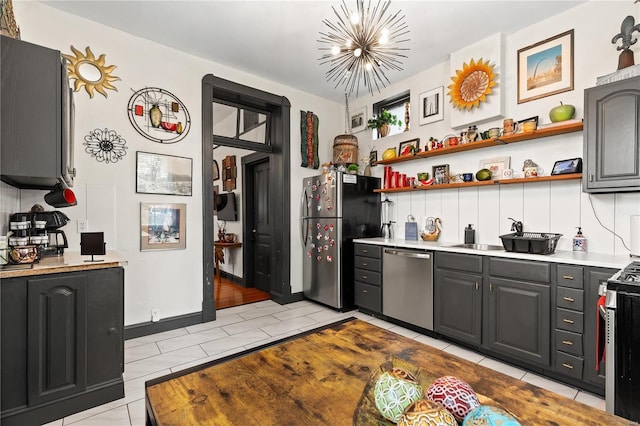 kitchen featuring stainless steel appliances, decorative backsplash, gray cabinets, a notable chandelier, and light tile patterned flooring