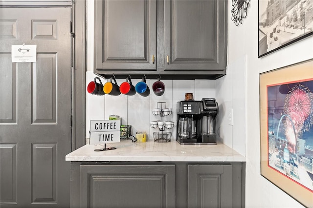 bar featuring decorative backsplash, light stone countertops, and gray cabinets