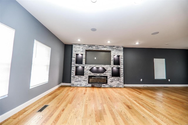 living room with hardwood / wood-style floors and a stone fireplace