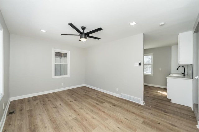 unfurnished room with sink, ceiling fan, and light hardwood / wood-style floors