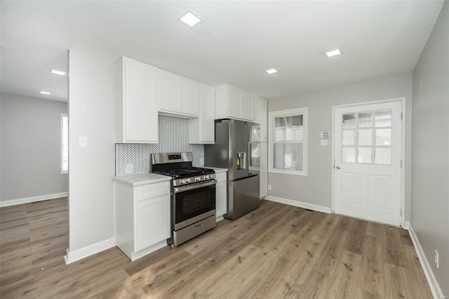 kitchen with stainless steel appliances, light hardwood / wood-style floors, decorative backsplash, and white cabinetry