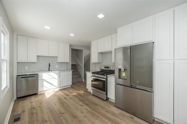 kitchen with appliances with stainless steel finishes, white cabinetry, and backsplash