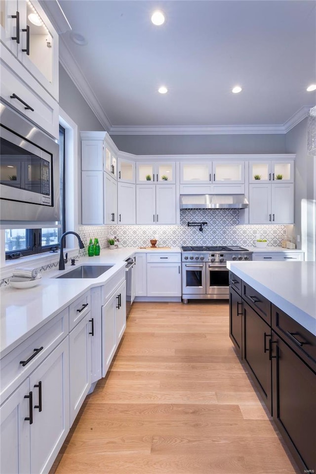 kitchen featuring white cabinetry, appliances with stainless steel finishes, and wall chimney exhaust hood