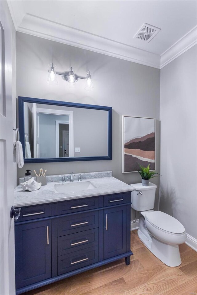 bathroom with hardwood / wood-style flooring, vanity, toilet, and crown molding