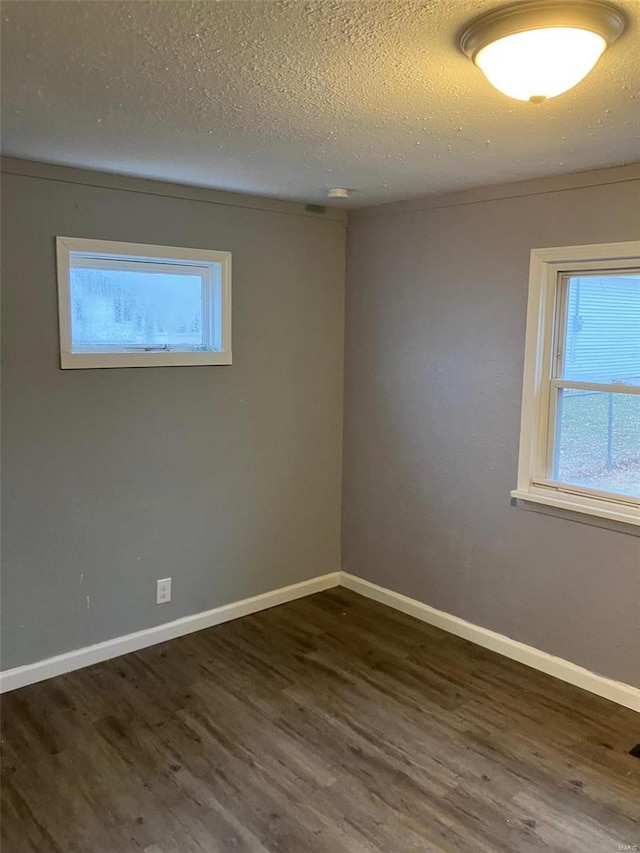 unfurnished room with dark wood-type flooring and a textured ceiling